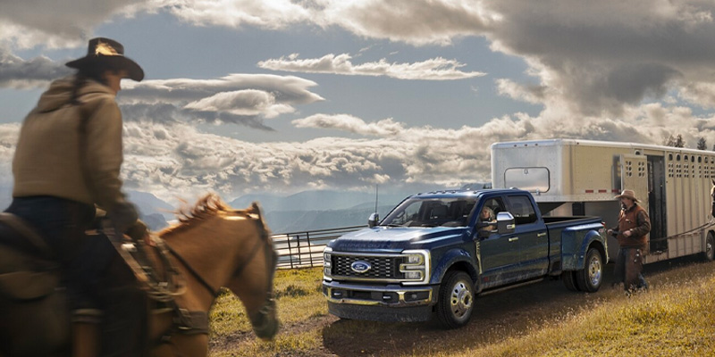 a blue 2025 ford -f250 on the hill with a cowboy