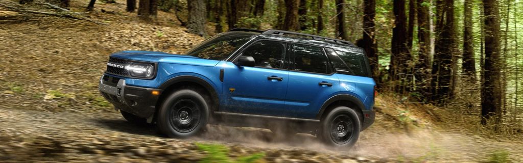 2026 Ford Bronco Sport compact SUV in motion on a forest trail, showcasing adventure-ready performance, advanced 4x4 capability, modern comfort, and versatile design.