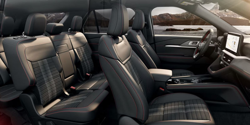 Interior view of a vehicle showing front and rear black leather seats with red stitching, center console, and dashboard touchscreen display