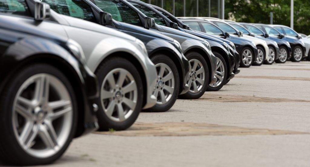 Side view of a row of certified pre-owned vehicles lined up in a dealership lot, highlighting multiple cars parked in sequence with polished exteriors and uniform presentation.
