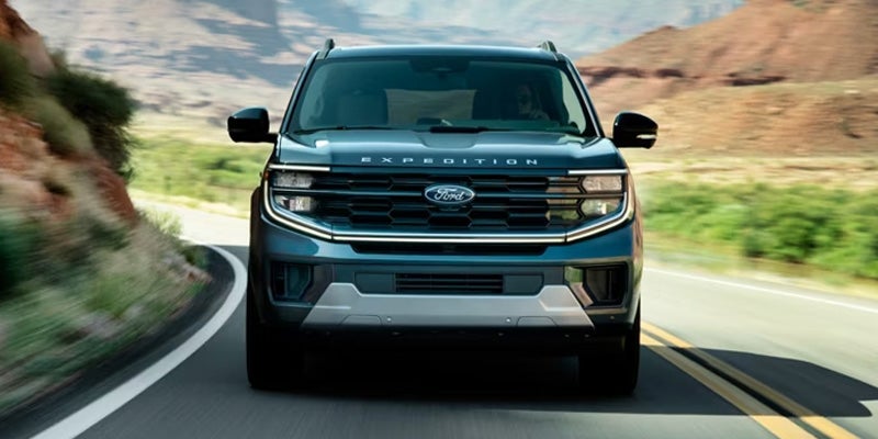 Ford Expedition SUV driving on a winding road through a scenic mountain landscape.