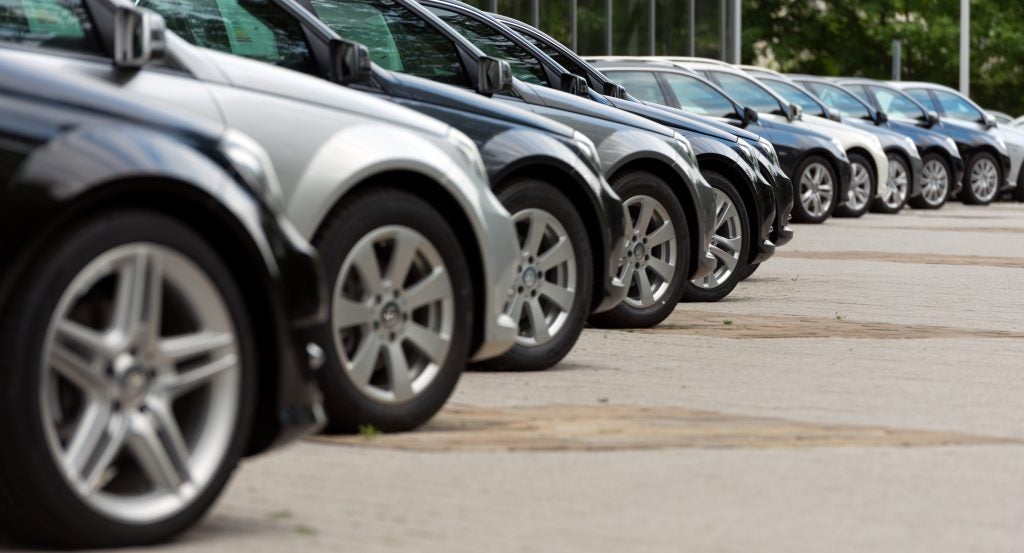 Row of parked vehicles lined up at an automotive dealership lot.